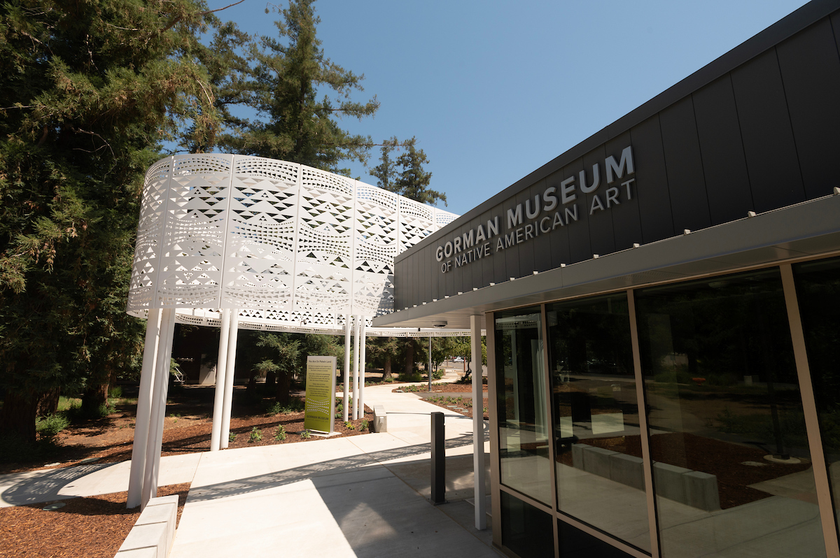The front of the Gorman Museum of Native American Art with large green trees in the background