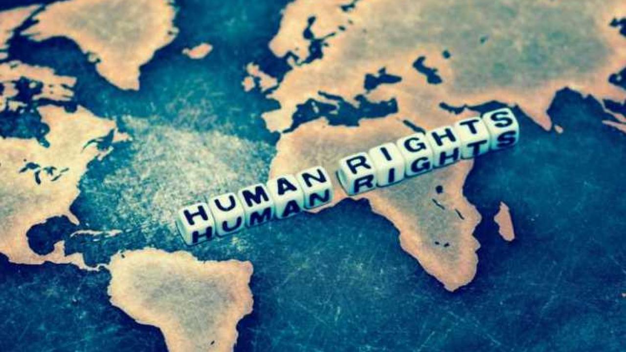 A blue and yellow portion of a world map, with the words "Human Rights" written in dice placed on top of the map.